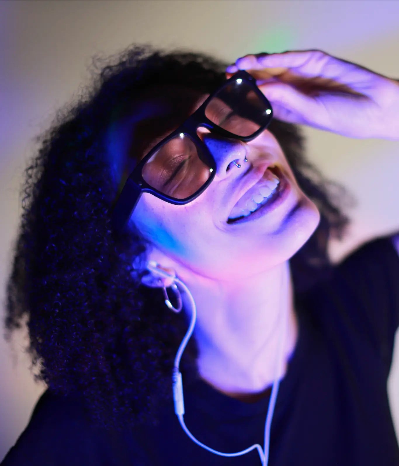 Woman smiling while wearing Healyan Glasses and wired headphones