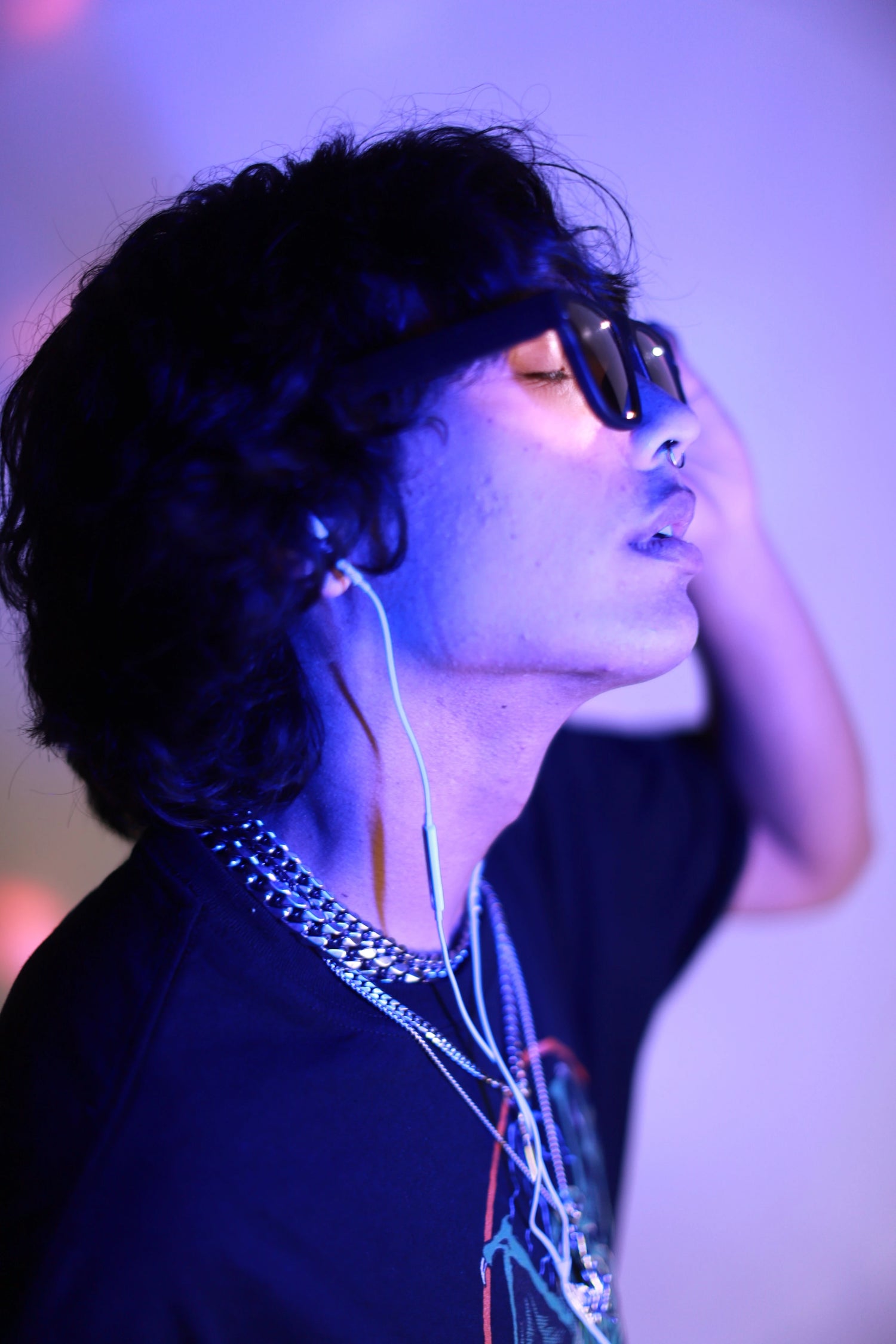 Male wearing Healyan's Glasses paired with wired headphones in purple light